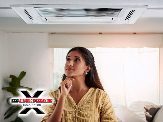 woman looking up at air duct ceiling in living room wondering look time to schedule cleaning